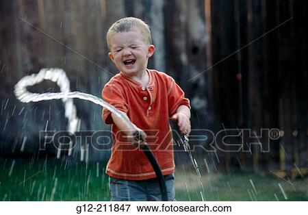 Boy (2 yr) playing with water hose. Idaho. USA View Large Photo Image Stock Photo - Boy (2 yr) playing with water hose. Idaho. USA. Fotosearch