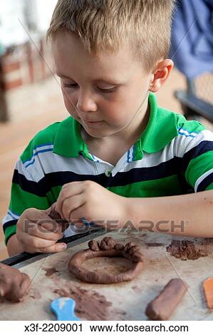 Stock Image - Boy age 5 working clay in backyard activity. St Paul Minnesota MN USA.. Fotosearch