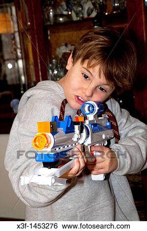 Stock Photograph - Boy age 7 shooting his new Star Wars General Grievous Blaster laser gun Christmas present St Paul Minnesota USA. Fotosearch
