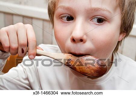 Boy age 8 licking chocolate off of wooden spoon St Paul Minnesota MN USA View Large Photo Image Picture - Boy age 8 licking chocolate off of wooden spoon St Paul Minnesota MN USA. Fotosearch