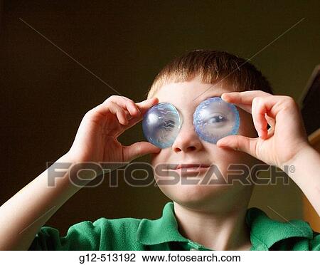 Boy, age five, holding clear blue plastic pieces to his eyes. View Large Photo Image Stock Image - Boy, age five, holding clear blue plastic pieces to his eyes.. Fotosearch