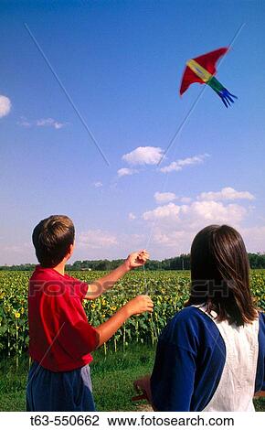 Stock Image - boy and girl flying a kite together. Fotosearch