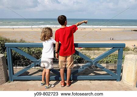 Boy and girl looking at the sea, Lacanau-Oc? an. Gironde, Aquitaine, France View Large Photo Image Stock Image - Boy and girl looking at the sea, Lacanau-Oc? an. Gironde, Aquitaine, France. Fotosearch