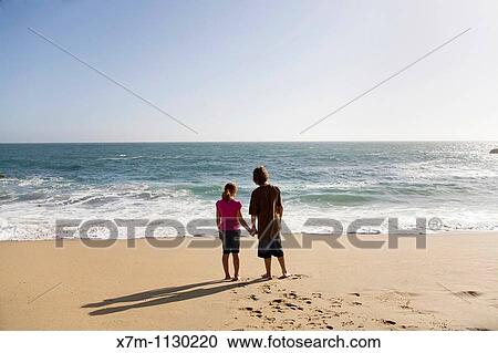 Boy and girl looking out contemplatively at the vast ocean as the sun begins to set in Santa Cruz, California View Large Photo Image Stock Image - Boy and girl looking out contemplatively at the vast ocean as the sun begins to set in Santa Cruz, California. Fotosearch