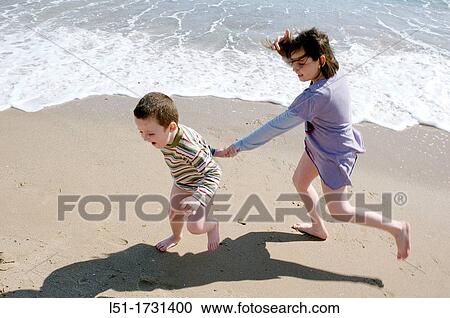 Stock Image - Boy and girl playing in the beach hand in hand, El Saler beach, Albufera de Valencia Nature reserve, Valencia, Spain. Fotosearch