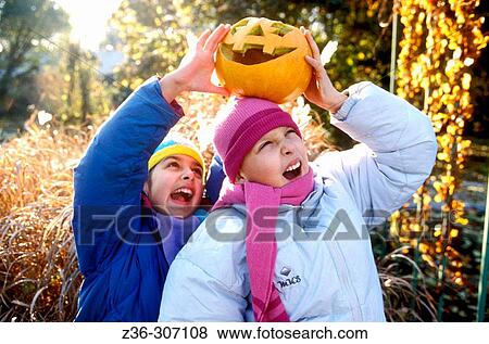 Stock Photo - Boy and girl playing with pumpkin in Halloween. Fotosearch