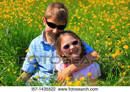 boy and girl sitting in blooming field View Large Photo Image Stock Image - boy and girl sitting in blooming field. Fotosearch
