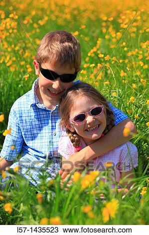 boy and girl sitting in blooming field View Large Photo Image Stock Image - boy and girl sitting in blooming field. Fotosearch