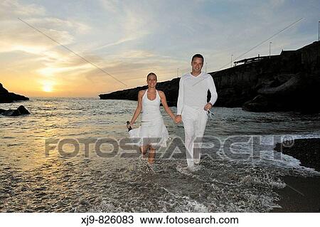 Stock Image - Boy and girl who toasting on the beach at Honeymoon. Fotosearch