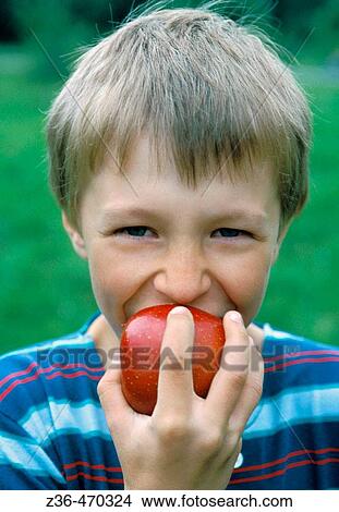 Boy biting an apple View Large Photo Image Picture - Boy biting an apple. Fotosearch