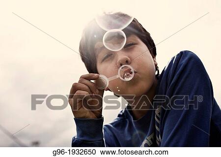 Stock Image - Boy blowing soap bubbles. Fotosearch