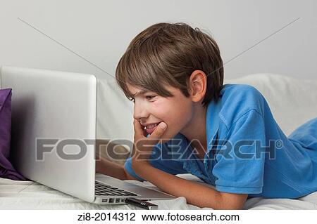 Stock Image - Boy chatting with friends online on laptop at home.. Fotosearch