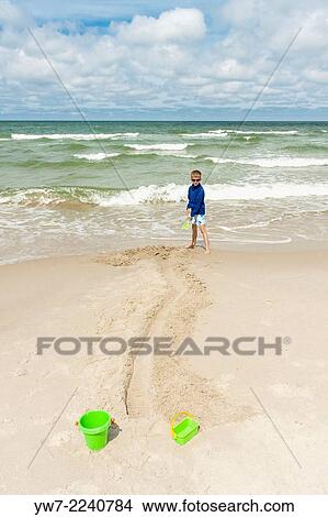 Picture - Boy digging canal on beach near Bialog? ra, Poland.. Fotosearch