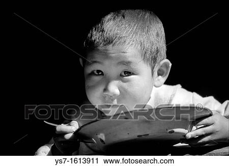 Stock Image - Boy eating in a hut close to Lukla village along the Everest trail, Khumbu region, Nepal, Asia. Fotosearch