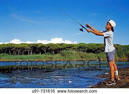Stock Photograph - Boy fishing at swamp, Castiglione della Pescaia. Maremma, Tuscany, Italy. Fotosearch