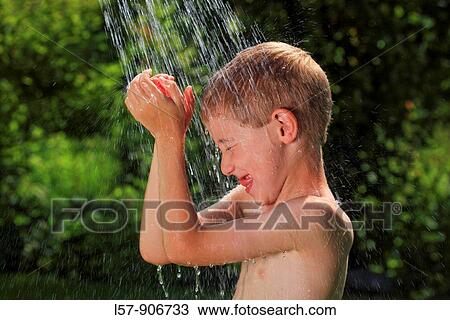 Stock Image - boy having shower outdoors, Switzerland. Fotosearch