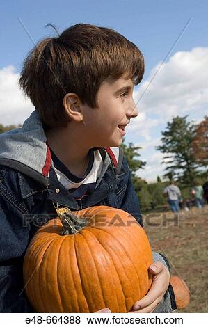 Boy holding pumpkin in pumpkin patch View Large Photo Image Stock Photo - Boy holding pumpkin in pumpkin patch. Fotosearch