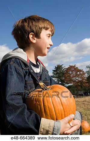 Boy holding pumpkin in pumpkin patch View Large Photo Image Stock Photo - Boy holding pumpkin in pumpkin patch. Fotosearch