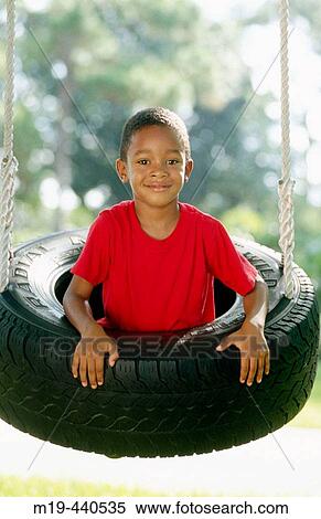 Stock Photography - boy in a tire swing. Fotosearch