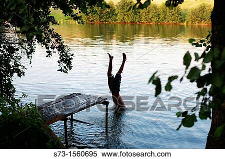 Boy jump from the pier in Lake Avral, Kirillovka, Samara Region, Russian Federation View Large Photo Image Stock Photography - Boy jump from the pier in Lake Avral, Kirillovka, Samara Region, Russian Federation. Fotosearch