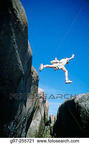 Stock Image - Boy jumping over abyss. Fotosearch