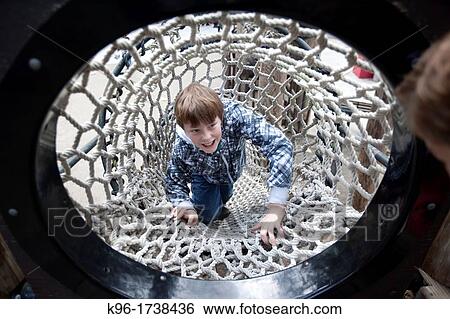 Stock Photograph - boy laughing while climbing a rope tunnel. Fotosearch