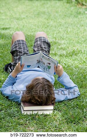 Boy laying on grass reading a book View Large Photo Image Stock Image - Boy laying on grass reading a book. Fotosearch