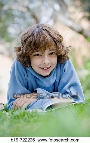 Boy laying on grass reading a book View Large Photo Image Stock Photograph - Boy laying on grass reading a book. Fotosearch