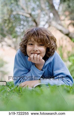 Boy laying on grass reading a book View Large Photo Image Stock Photography - Boy laying on grass reading a book. Fotosearch
