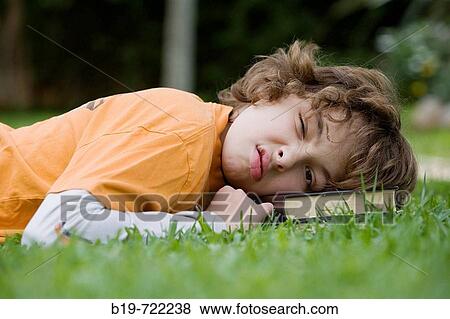 Stock Photo - Boy laying on grass. Fotosearch