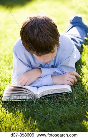 Boy laying on the grass reading a book View Large Photo Image Stock Photograph - Boy laying on the grass reading a book. Fotosearch