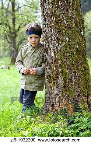 Boy leaning on a tree playing outdoor. View Large Photo Image Stock Image - Boy leaning on a tree playing outdoor.. Fotosearch