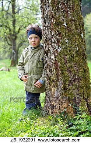 Boy leaning on a tree playing outdoor. View Large Photo Image Stock Image - Boy leaning on a tree playing outdoor.. Fotosearch