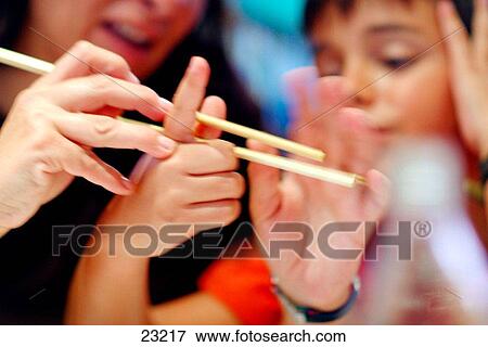 Stock Photo - Boy learning tu use chopsticks at chinese restaurant. Fotosearch