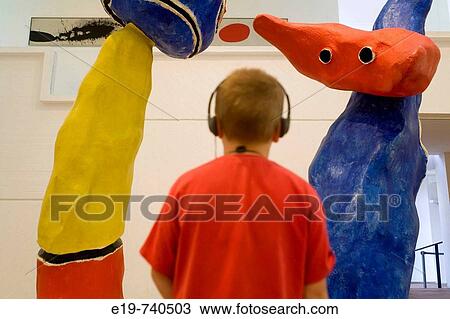 Stock Image - Boy listening to audio guide studying Miro sculpture. Miro Foundation, Barcelona, Spain. Fotosearch