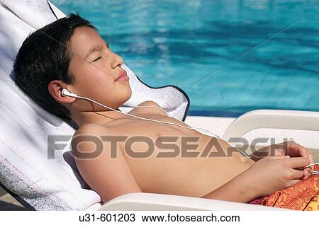 Boy listening to music alongside a swimming pool View Large Photo Image Stock Image - Boy listening to music alongside a swimming pool. Fotosearch