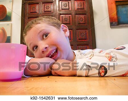 Boy making a funny face while sitting at a table. View Large Photo Image Stock Image - Boy making a funny face while sitting at a table.. Fotosearch