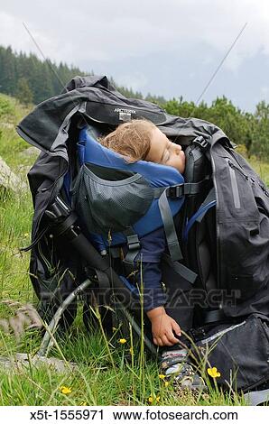 Stock Image - Boy of two asleep in a backpack baby carrier Photogrpahed in the Austrian Alps. Fotosearch