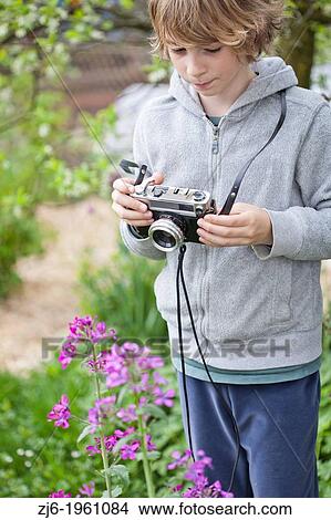 Picture - Boy photographing flowers in the garden.. Fotosearch
