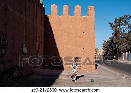 Boy playing football in front of the adobe medina wall, Tiznit, Morocco. View Large Photo Image Stock Image - Boy playing football in front of the adobe medina wall, Tiznit, Morocco.. Fotosearch