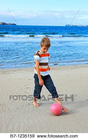 Stock Photo - boy playing football on beach, Sutherland, Scotland. Fotosearch