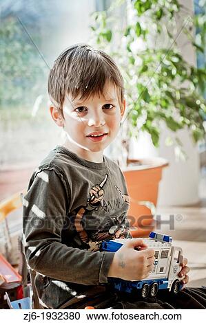 Stock Image - Boy playing indoor with toy truck.. Fotosearch