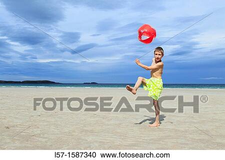 Stock Image - boy playing on sandy beach, Sutherland, Scotland. Fotosearch