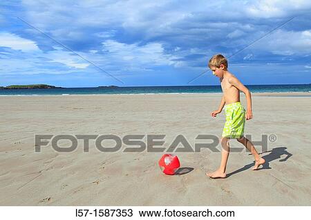 Stock Image - boy playing on sandy beach, Sutherland, Scotland. Fotosearch