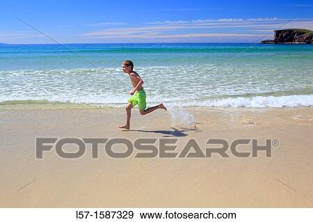 Stock Photo - boy playing on sandy beach, Sutherland, Scotland. Fotosearch