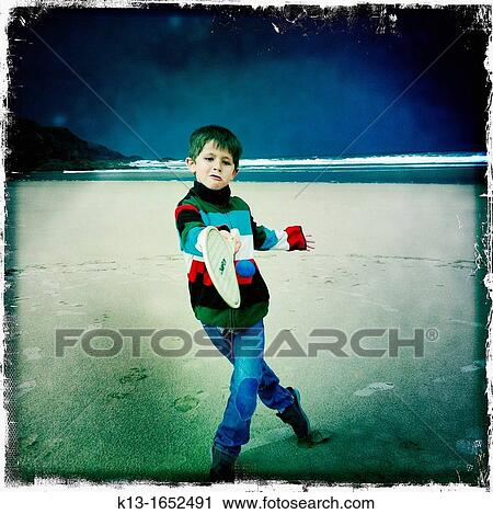 Stock Image - Boy playing tennis in Odeceixe beach in Alentejo, Portugal. Fotosearch