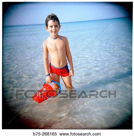 Boy playing with a bucket in the water View Large Photo Image Stock Photography - Boy playing with a bucket in the water. Fotosearch