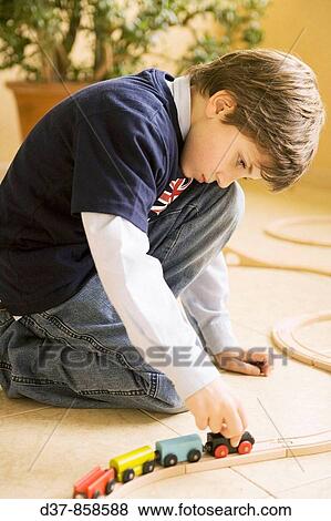 Boy playing with a toy train at home View Large Photo Image Stock Photo - Boy playing with a toy train at home. Fotosearch