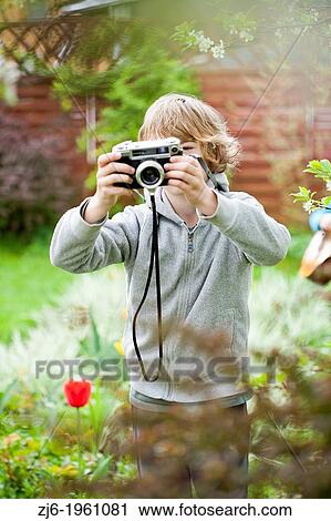 Stock Image - Boy playing with an old camera.. Fotosearch