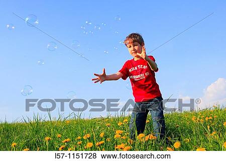 Stock Photo - boy playing with bubbles in field of Dandelions, Zuercher Oberland, Zuerich, Switzerland. Fotosearch